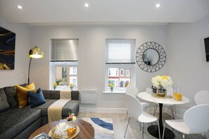 A modern living room with a sofa, a coffee table, and a dining area with chairs and a table.