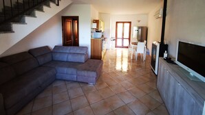 Un salon avec un canapé, un téléviseur et un escalier.