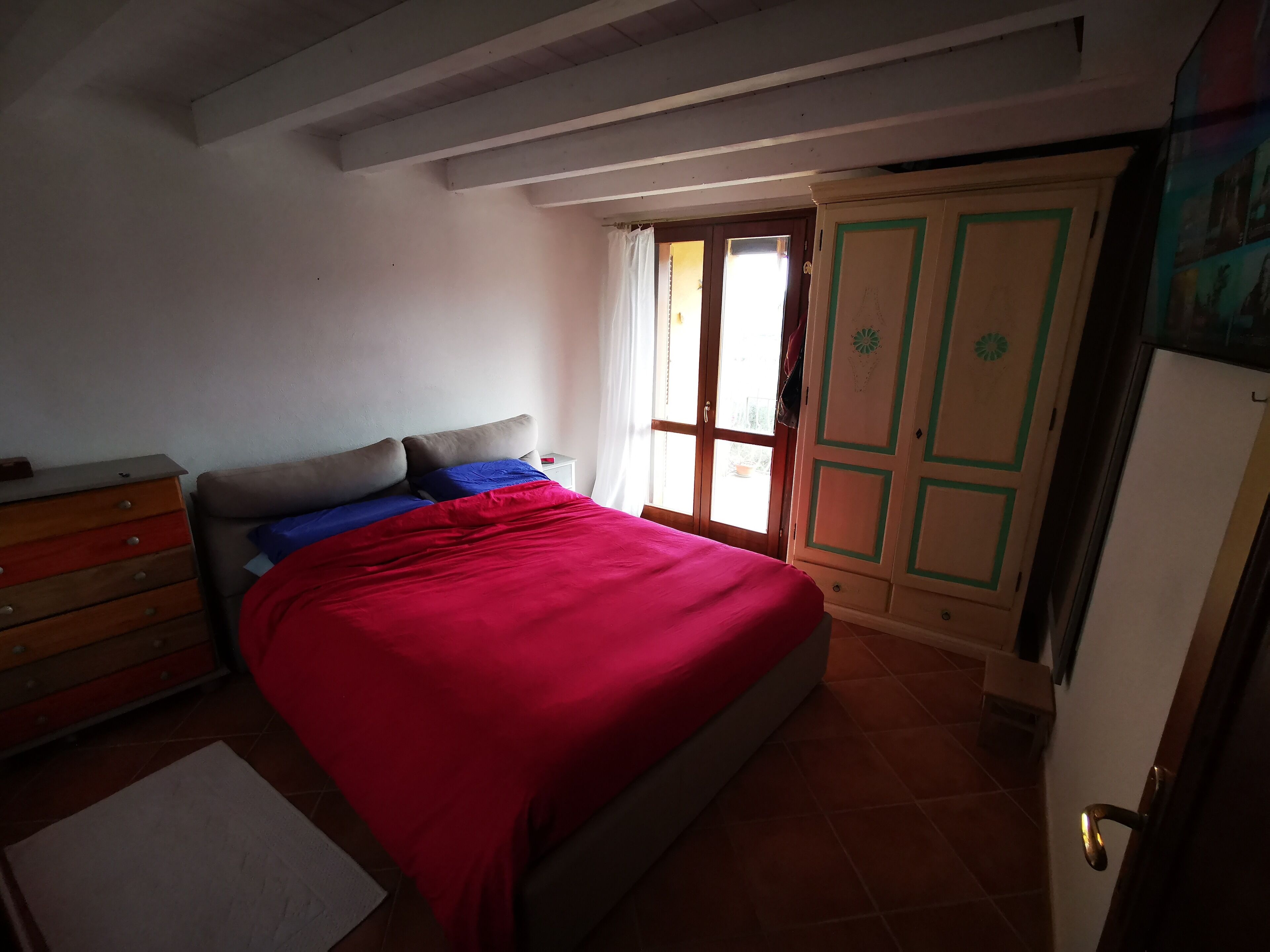 Une chambre à coucher comprenant un lit, une commode, une armoire et une fenêtre avec des rideaux.