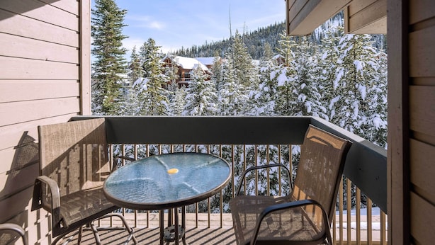 A balcony with a table and chairs, overlooking a snowy mountain landscape. - Steps to Ski Lifts - Condo w/ Walk-Out Patio! (Big Sky)