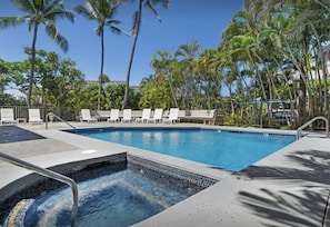 A swimming pool with lounge chairs, surrounded by palm trees and a clear sky. - Apartment in town-walking distance to everything (Kailua-Kona)