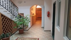 A hallway with a staircase, potted plants, a fire extinguisher, and a patterned rug. - City Wall Hotel (Nairobi)