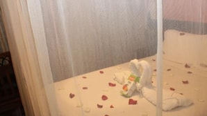A bed with rose petals and a white towel, suggesting a romantic setting. - City Wall Hotel (Nairobi)