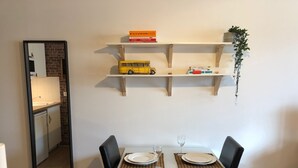 A dining area with a table set for two, a mirror, and a shelf with books and a toy bus. - Studio with balcony & free parking (Tours)