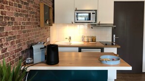 A kitchen with a brick wall, a microwave, a sink, and a wooden countertop. - Studio with balcony & free parking (Tours)
