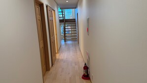 A narrow hallway with wooden doors on one side and a fire extinguisher on the other. - Picollo Mondo (Yamanakako)