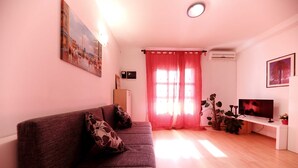 A living room with a sofa, a TV, and a window with curtains. - Apartments Melita (Zadar)