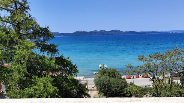 A balcony with a view of the sea, a distant mountain range, and some greenery. - Apartments Melita (Zadar)