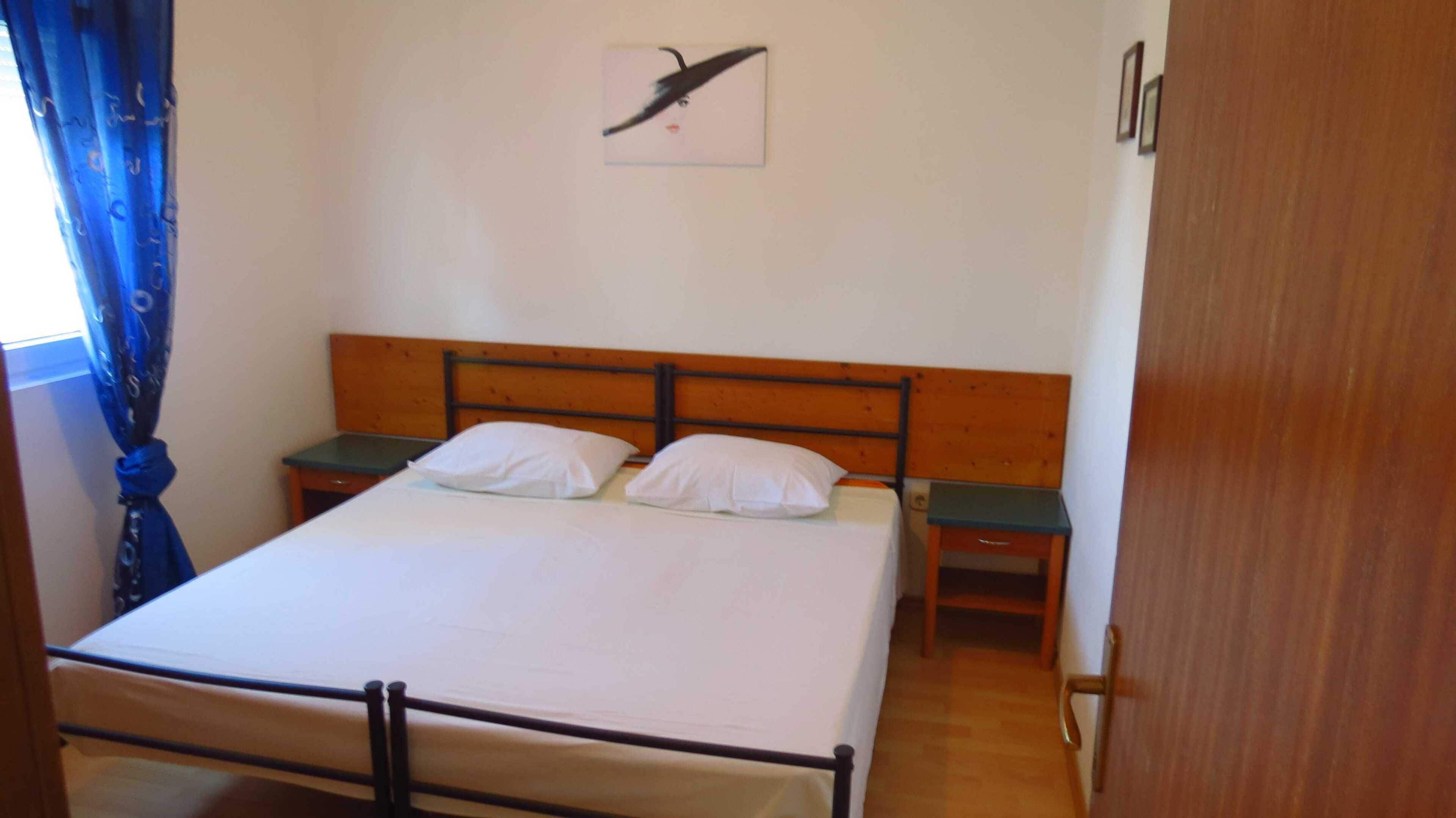 Ein Einzelbett mit Holz-Kopfteil, zwei Nachttische und ein an der Wand befestigtes Kunstwerk.