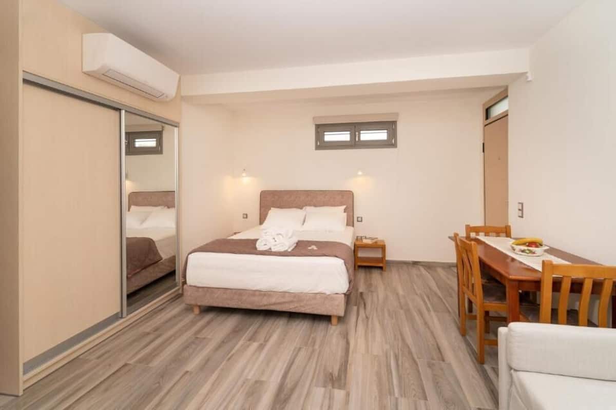 A bedroom with a bed, bedside table, and a small dining table with chairs.