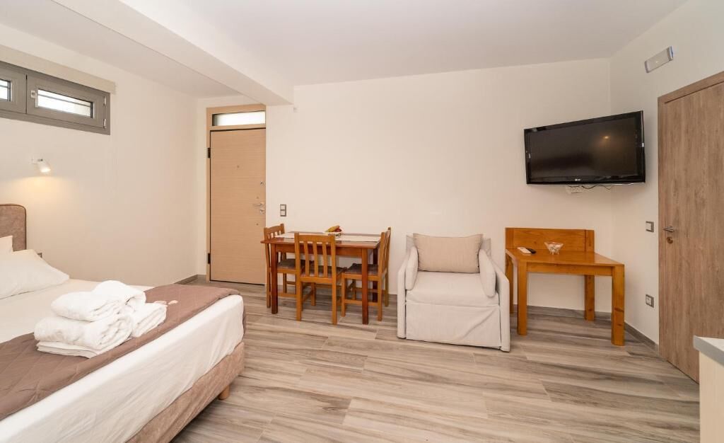 A bedroom with a bed, a desk, a chair, a TV, and a wardrobe.