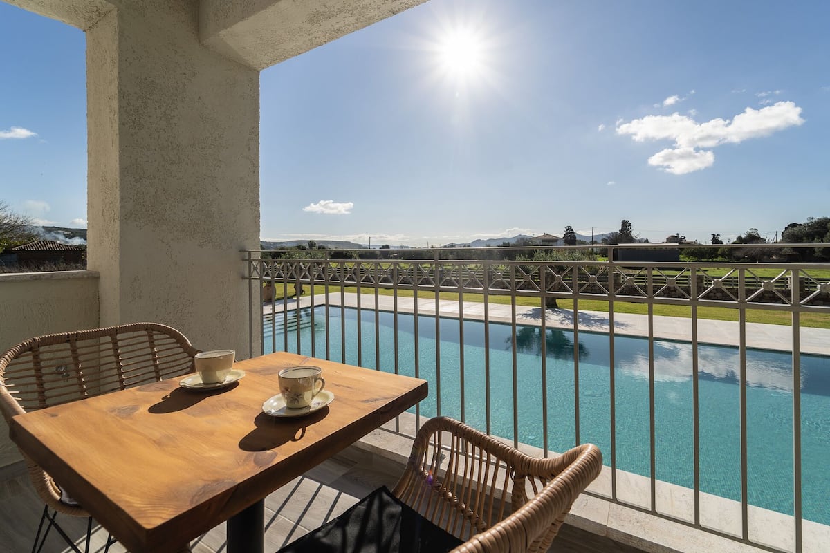 A wooden table with chairs and a view of a swimming pool.