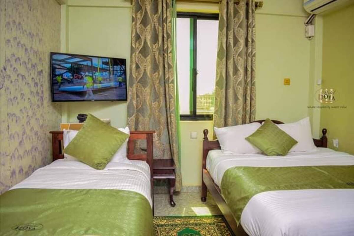 Una habitación de hotel con dos camas, televisión, ventana con cortinas y una mesita.