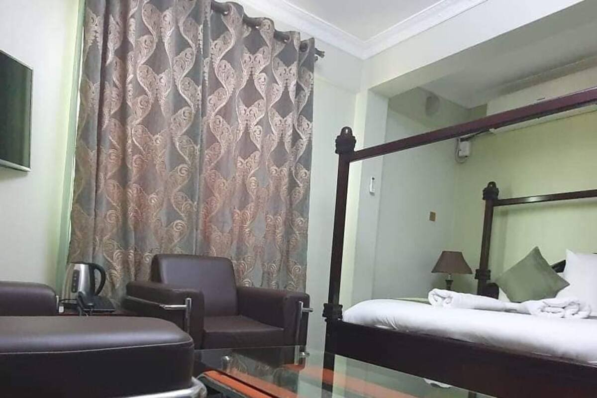 Una habitación de hotel con una cama, una silla, una mesa y una cortina.