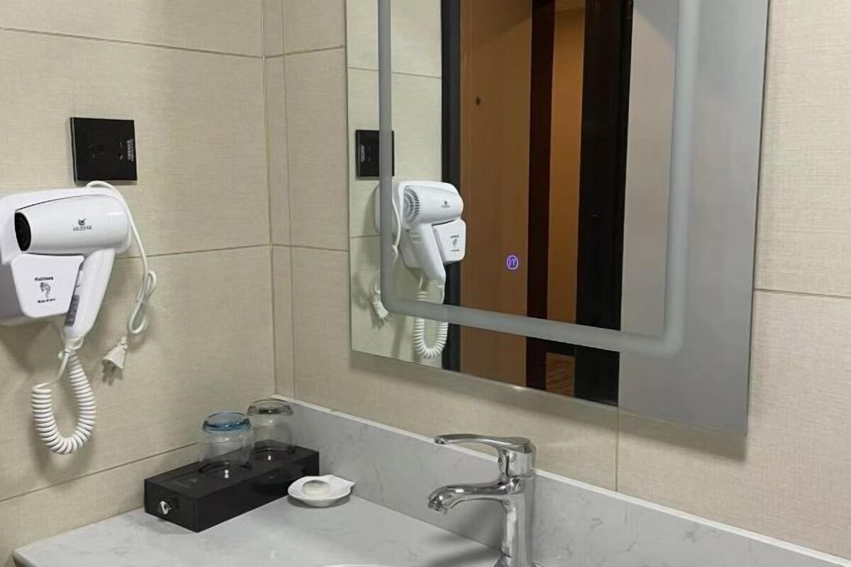 Un baño con espejo, lavamanos, secador de pelo y teléfono.