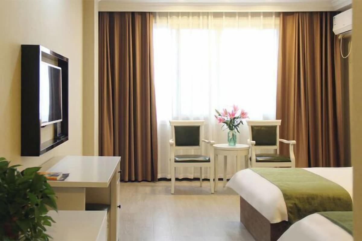 A hotel room with a bed, two chairs, a desk, and a TV.