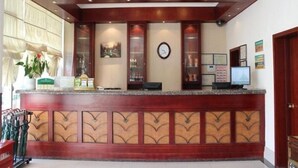 Een receptiebalie met een houten afwerking, een klok, ingelijste certificaten en een scherm.