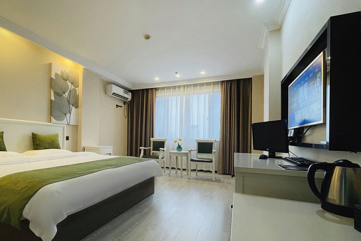 A hotel room with a bed, a desk, a television, and an air conditioning unit.