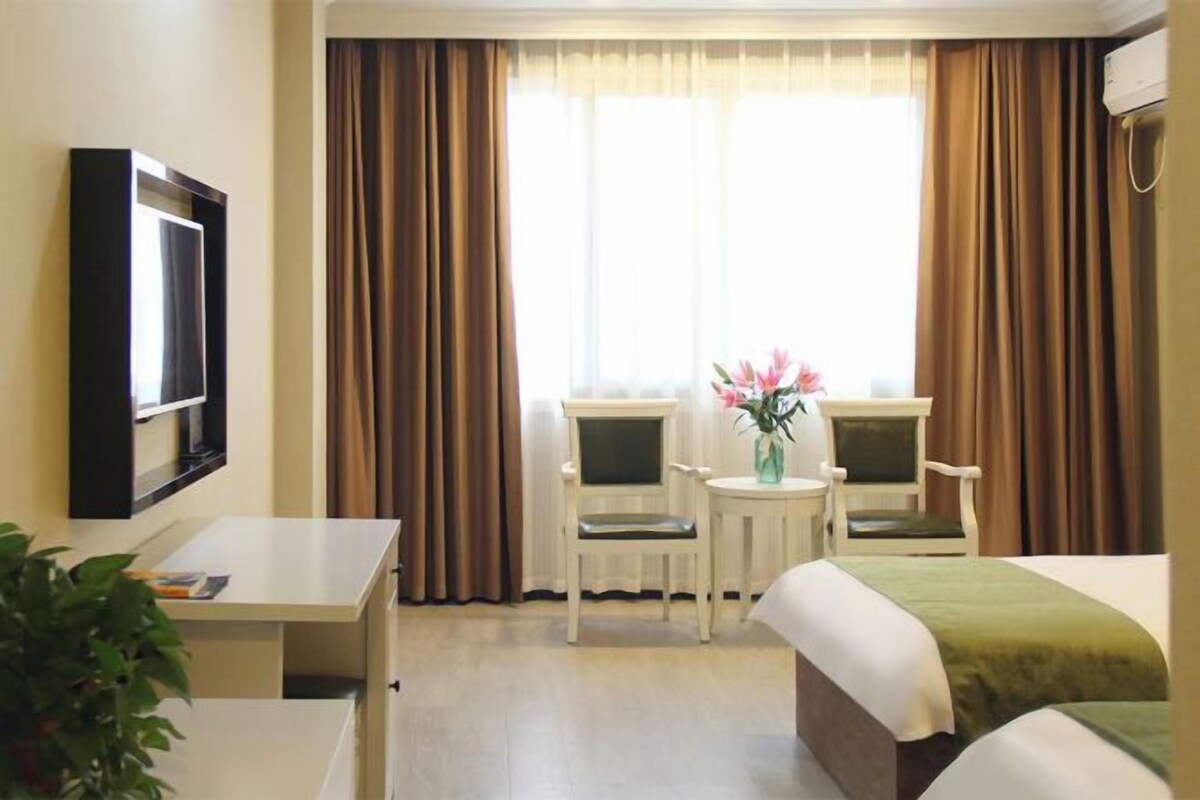 Una habitación de hotel con una cama, dos sillas, un escritorio y un televisor.