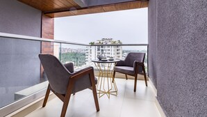 Un balcon avec deux chaises et une petite table, donnant sur un paysage urbain.