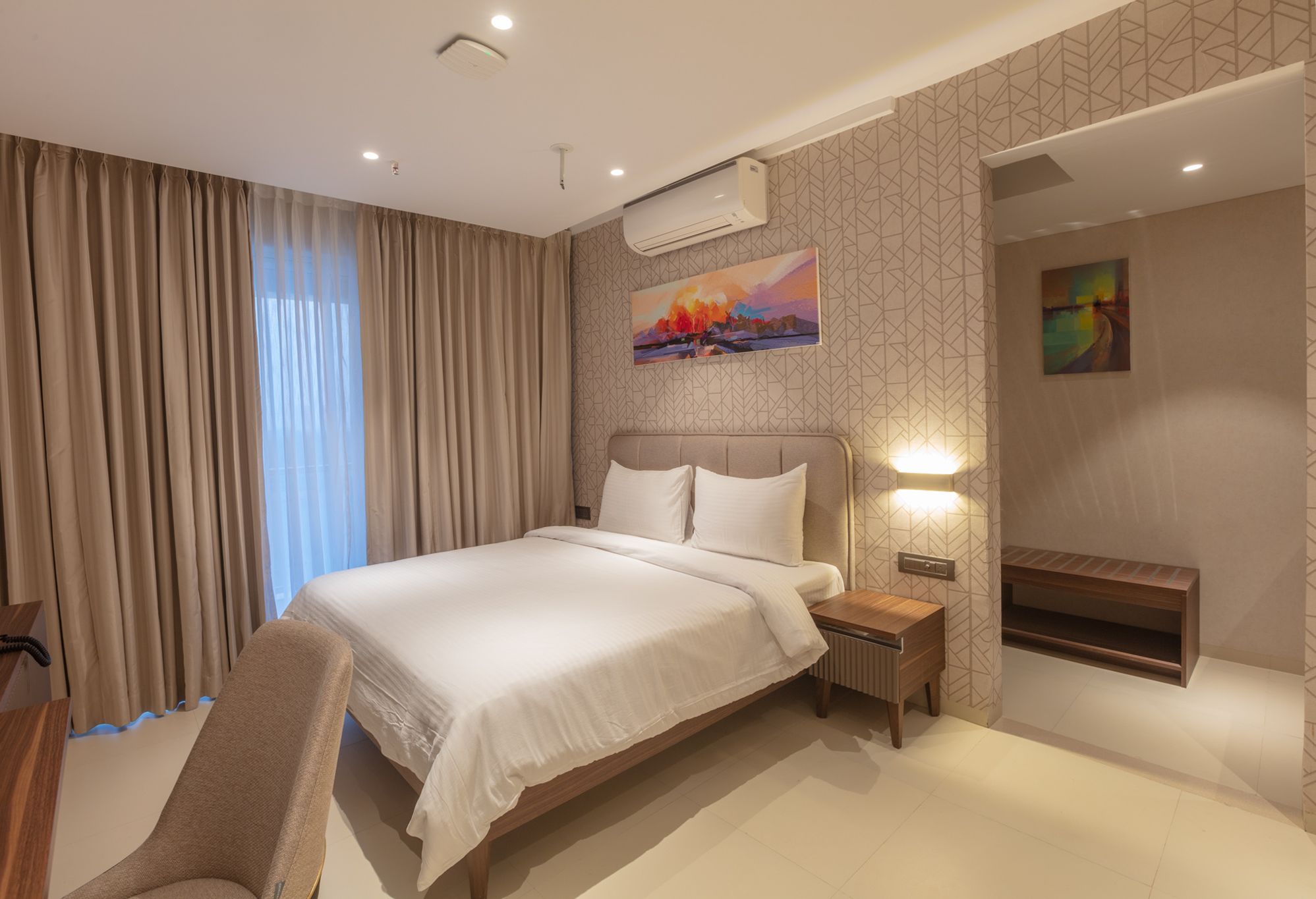 Una habitación de hotel moderna con una cama grande, un escritorio, una silla y un televisor.