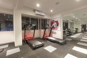 Uma academia com esteiras, um cartaz e equipamentos de ginástica.