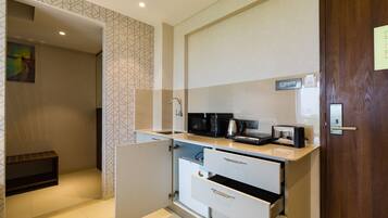 A compact kitchenette with a microwave, toaster, and coffee maker on the countertop.