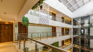 Un intérieur à plusieurs niveaux, doté de rampes en verre, de sols en marbre et d’un atrium central agrémenté d’une plante suspendue.