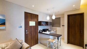 A compact kitchen with a central island, wooden doors, and a dining area with stools.