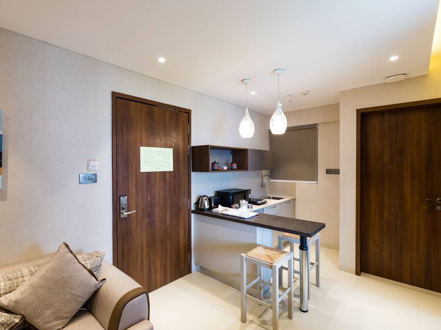 A compact kitchen with a central island, wooden doors, and a dining area with stools.