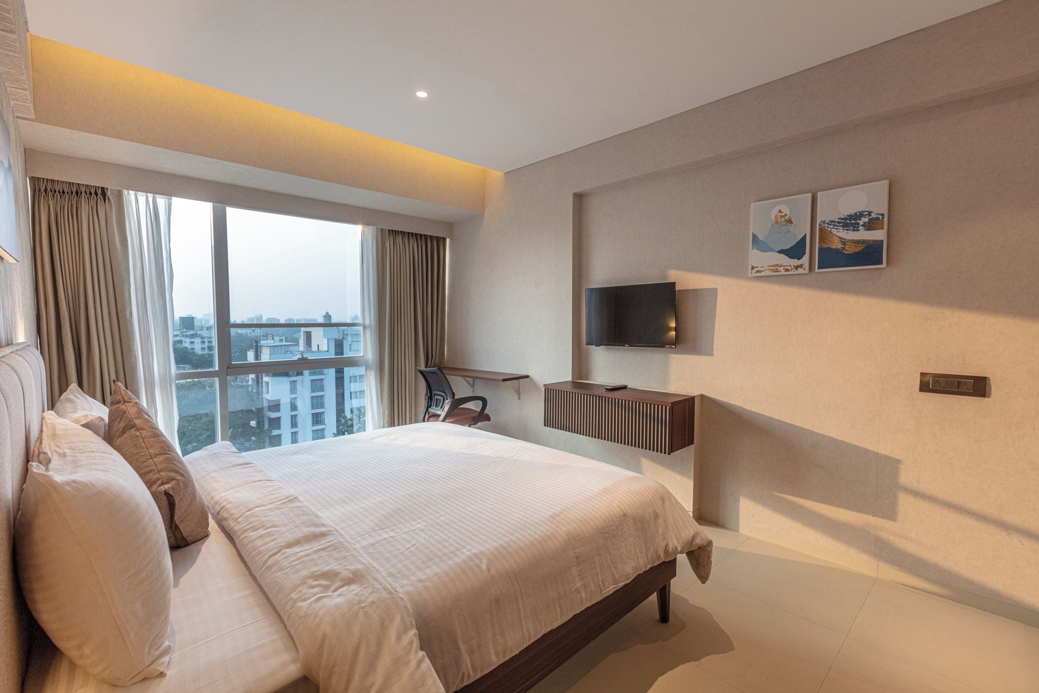 Habitación de hotel moderna con una cama grande, un escritorio, un televisor de pantalla plana y vistas a la ciudad.