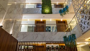 Un atrium à plusieurs niveaux, doté de sols en marbre, de jardinières verdoyantes et d’une cloison en bois.
