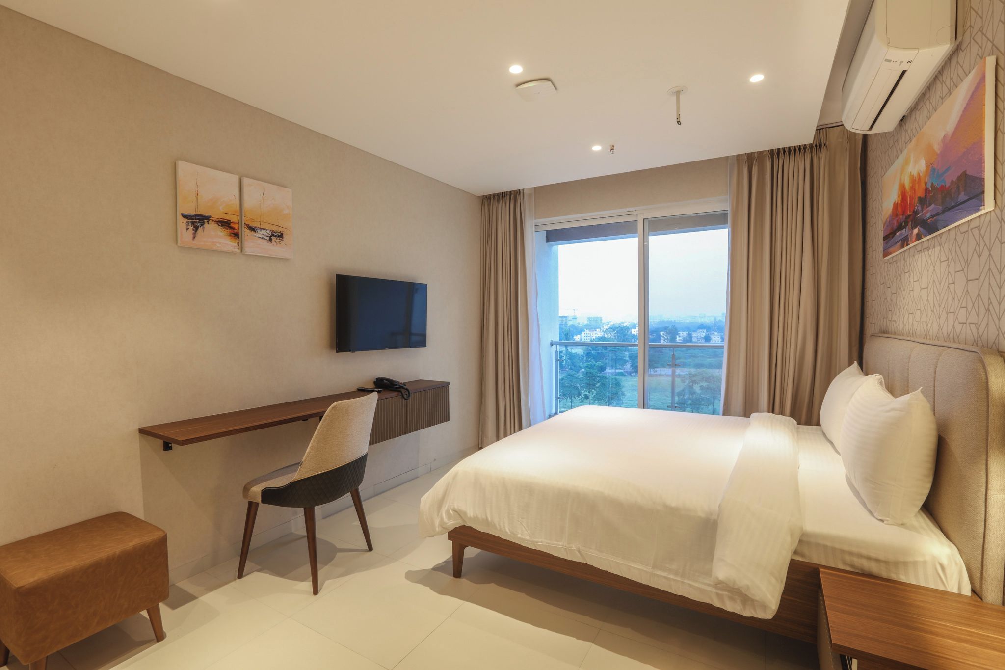 A hotel room with a bed, a desk, a chair, a TV, and a window with curtains.