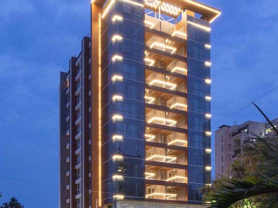 A modern high-rise building with multiple floors, large windows, and a prominent illuminated entrance.