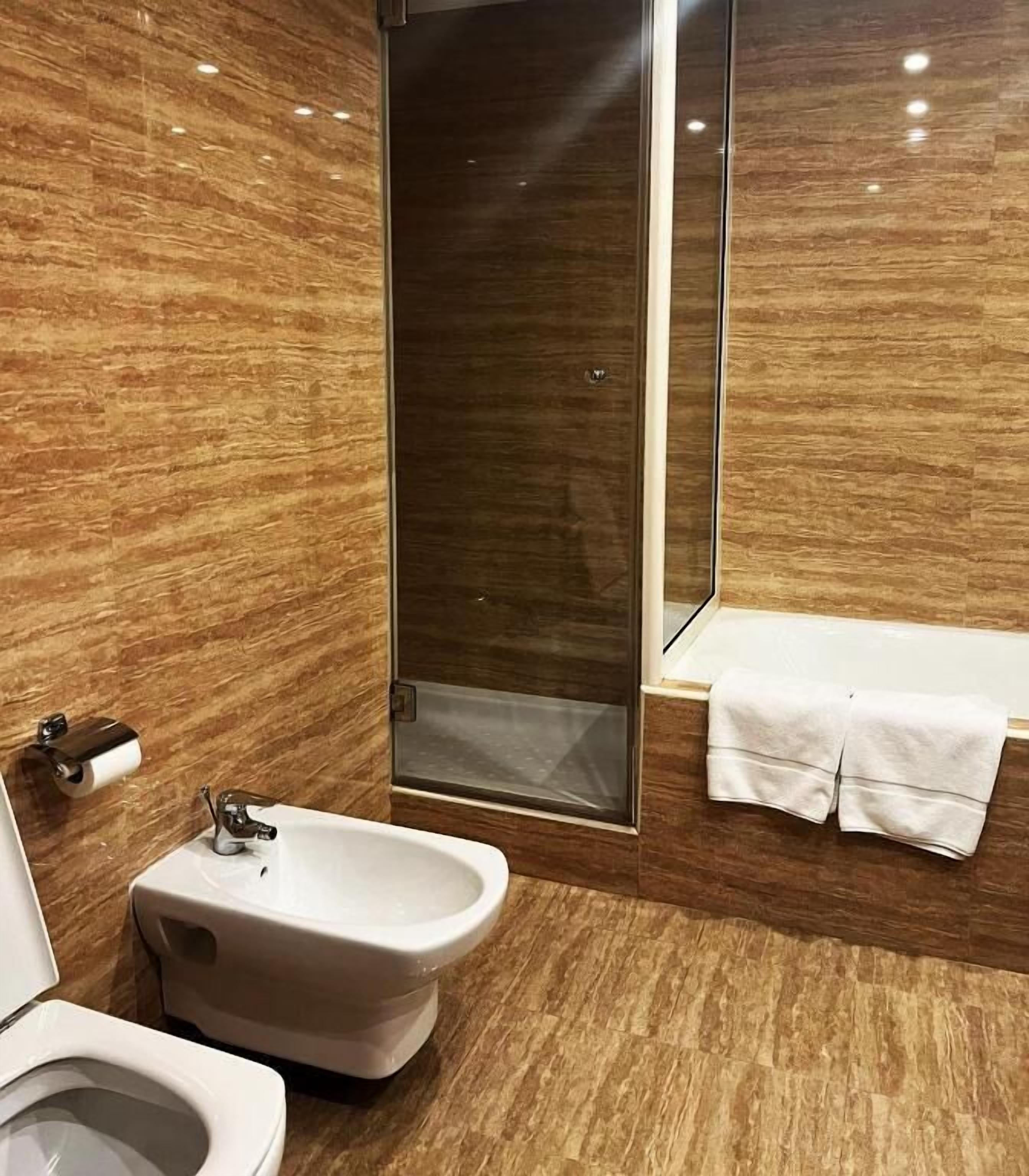 A bathroom with a bidet, a toilet, a shower, and a bathtub.