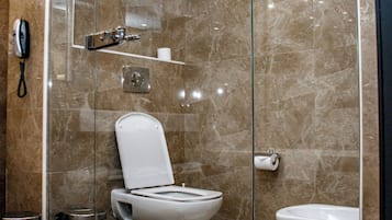 Un baño moderno con ducha de vidrio, inodoro y bidé.