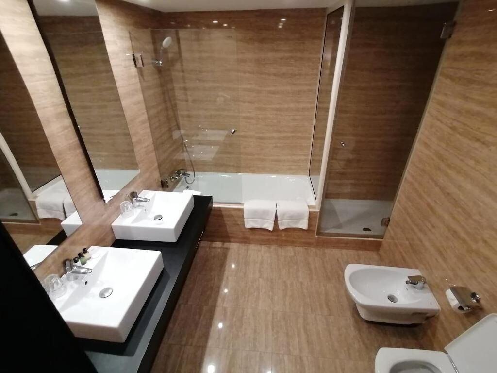 A modern bathroom with two sinks, a bathtub, a shower, and a toilet.