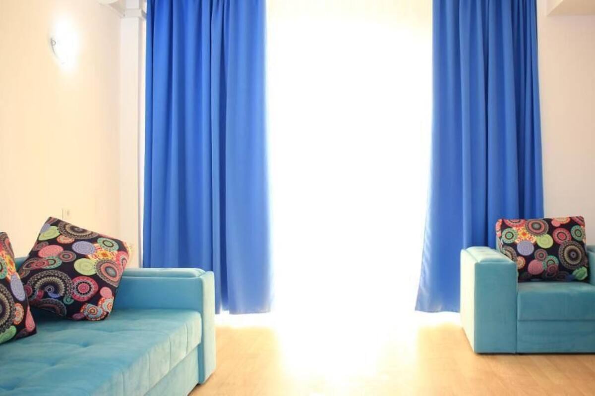 A room with two blue sofas, each with colorful patterned cushions, and a small black table.