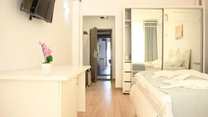A modern hotel room with a bed, a desk, a potted plant, and a wardrobe. - Hotel Pasha (Eforie)