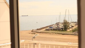 A marina with boats docked, a sandy beach, and a ship in the distance. - Hotel Pasha (Eforie)