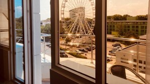 A view of a Ferris wheel from a window, with a parking lot and buildings in the background. - Hotel Pasha (Eforie)