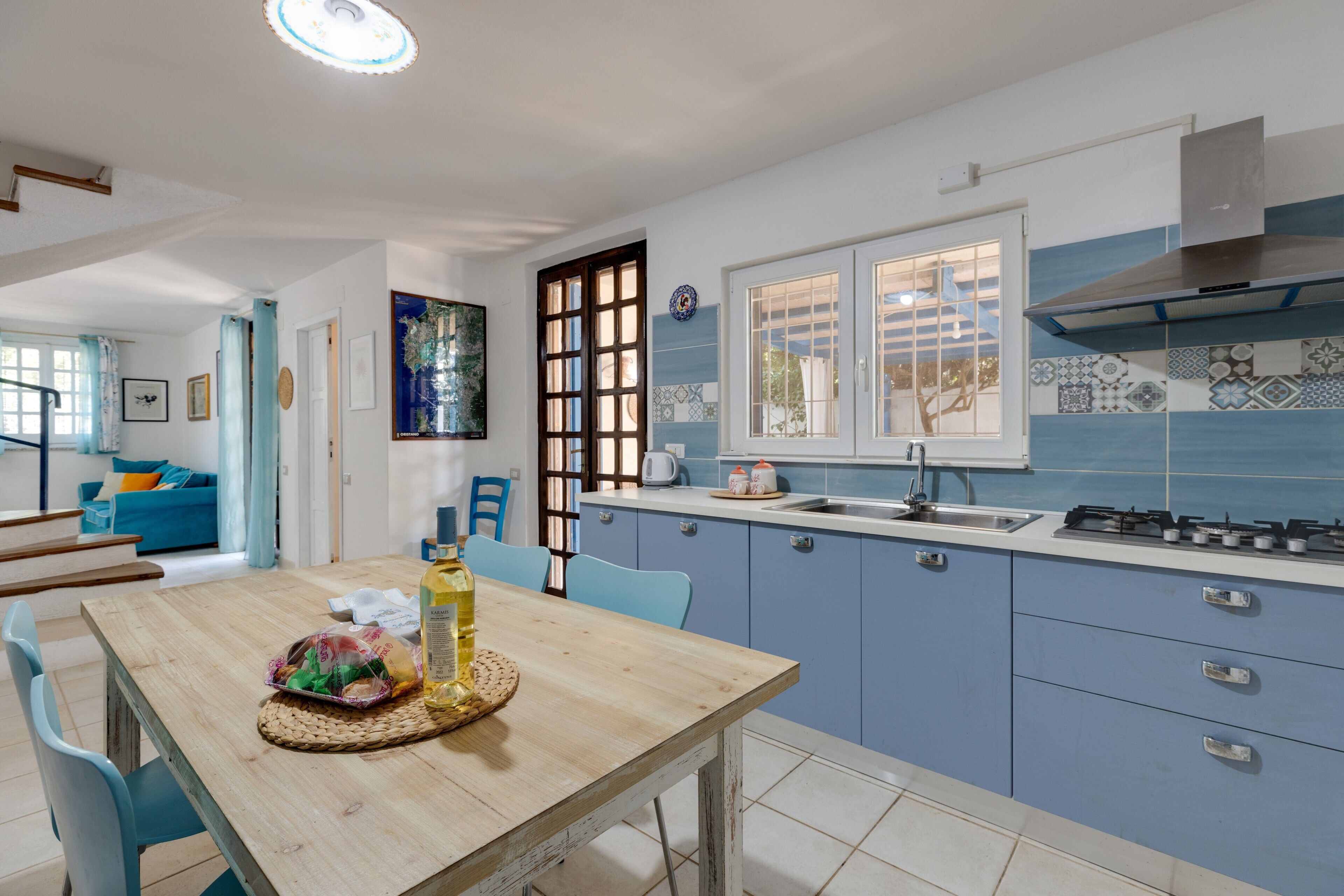 Une cuisine avec des armoires bleues, une table en bois et une fenêtre.