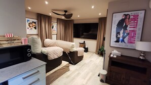Un dormitorio moderno con cama, mesitas de noche, televisor, un cartel y ventilador de techo.