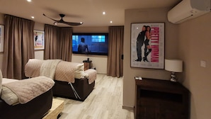Una habitación de hotel moderna con cama, zona de estar, televisión y chimenea.
