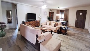 Una sala de estar con sofá, una mesa de centro, televisor y un comedor con sillas y mesa.