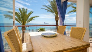 A wooden table with chairs, a view of the sea, and palm trees. - Holiday Apartment "WG1 Benidorm" Near the Beach with Sea View, Balcony, Air Conditioning and Wi-Fi (Benidorm)