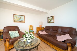 Ein Wohnzimmer mit zwei braunen Ledersofas, einem Glastisch und zwei Bildern an den Wänden.