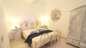 Une chambre à coucher comprenant un lit, des tables de chevet, une armoire et un élément décoratif mural.