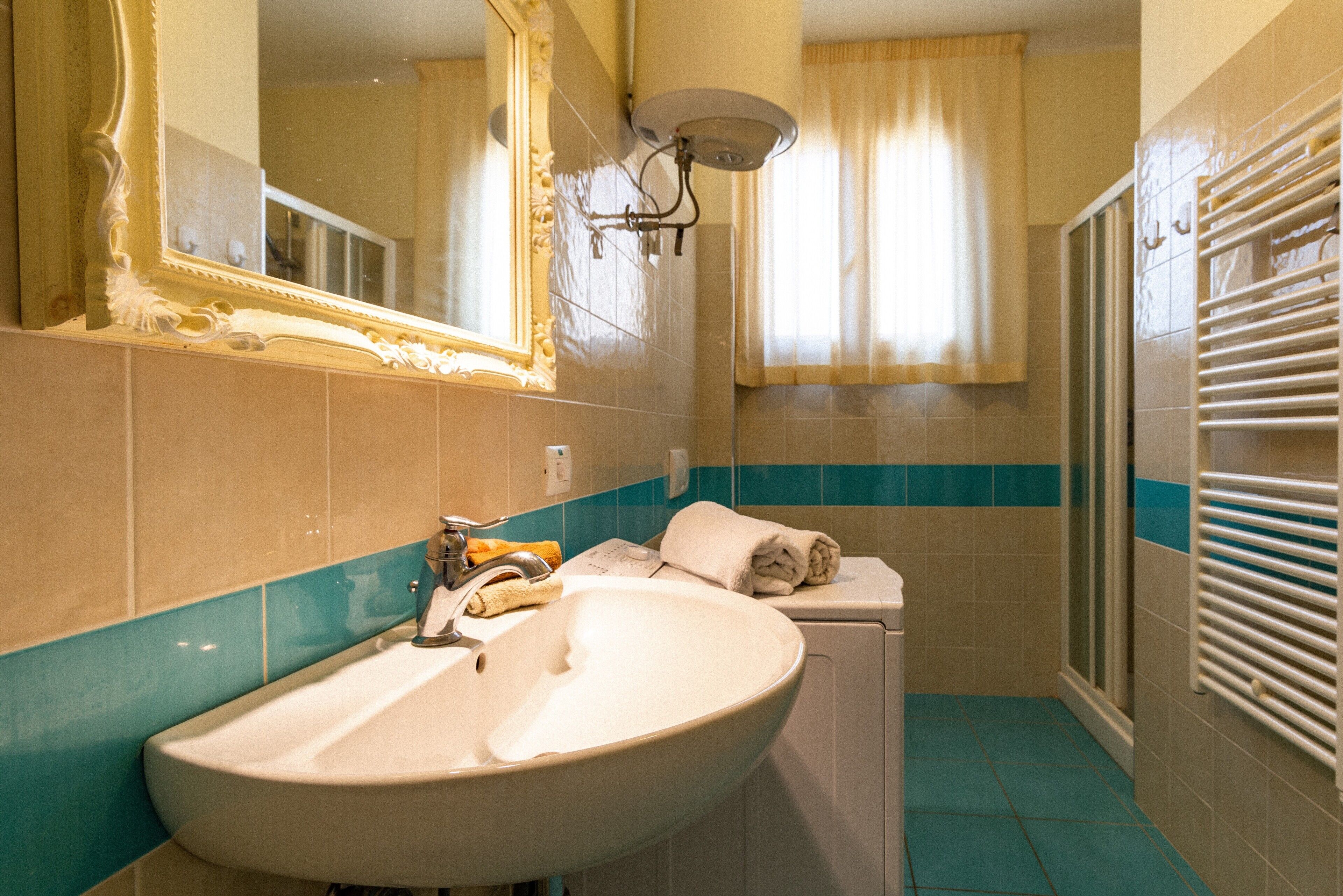 A bathroom with a sink, mirror, towel rack, and shower.