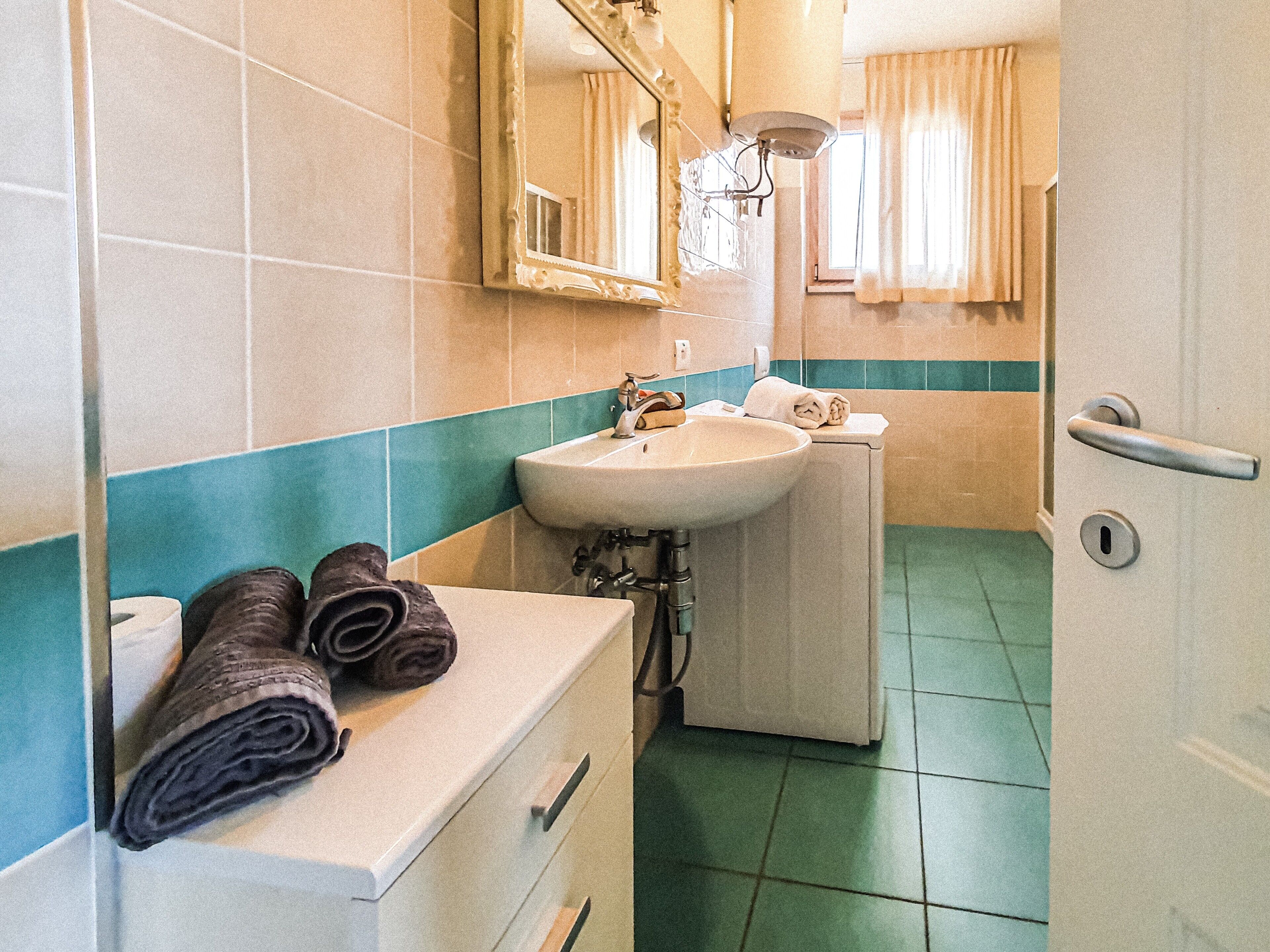 Ein Badezimmer mit Waschbecken, Spiegel, Handtuchhalter und einer Tür.